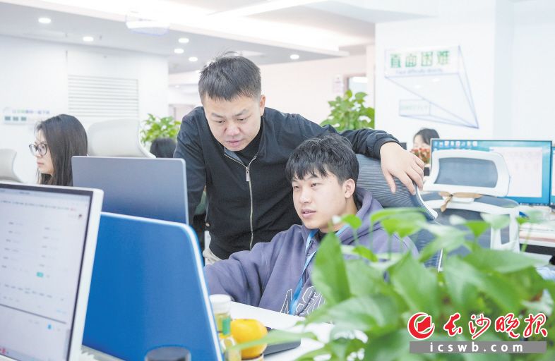 　　肖奇(站立者)正在向公司团队成员确认工作进度。长沙晚报全媒体记者 何文瑞 摄