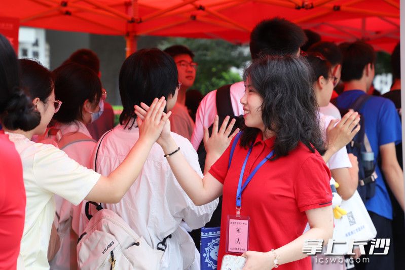 在长沙市一中双语实验学校,穿着红衣的老师跟进考场的学生击掌加油。 长沙晚报通讯员 谢雨娜 摄