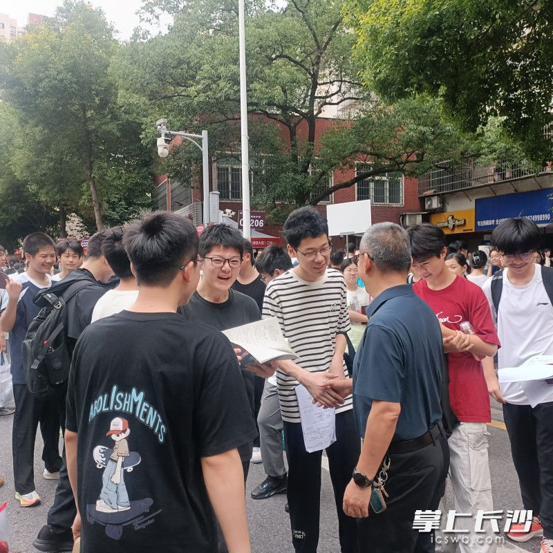 长沙市实验中学党委书记肖建军把考生送到考场,握个手传递满满的祝福。