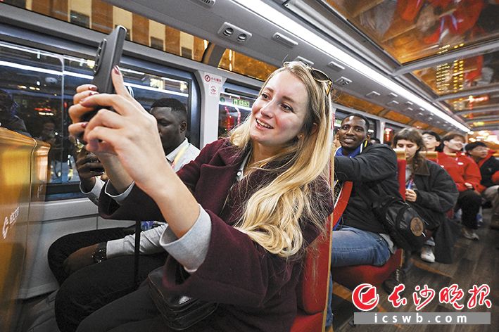  大家登上双层观光巴士夜游长沙，拿出手机拍下沿途美丽夜景。