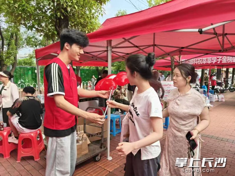 6月7日,在南雅中学考点外,来自湖南农业大学与东山街道的志愿者一起,搭建爱心加油站,开展爱心送考活动,为考生和家长送上饮用水、应急药品与祝福气球。长沙晚报全媒体记者 陈焕明 通讯员 刘晶 摄影报道