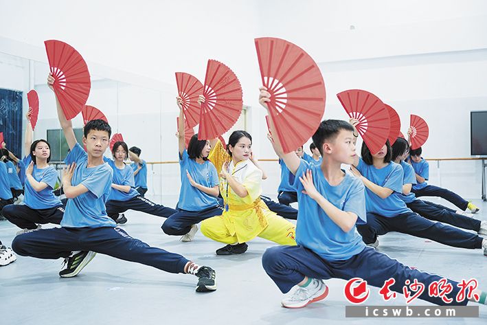 同学们手持红扇，在体育老师李攀美的指令下，弓步冲拳、云手转身、开扇收扇，一招一式尽显中华武术的刚柔并济。                                        长沙晚报全媒体记者 林暘 摄