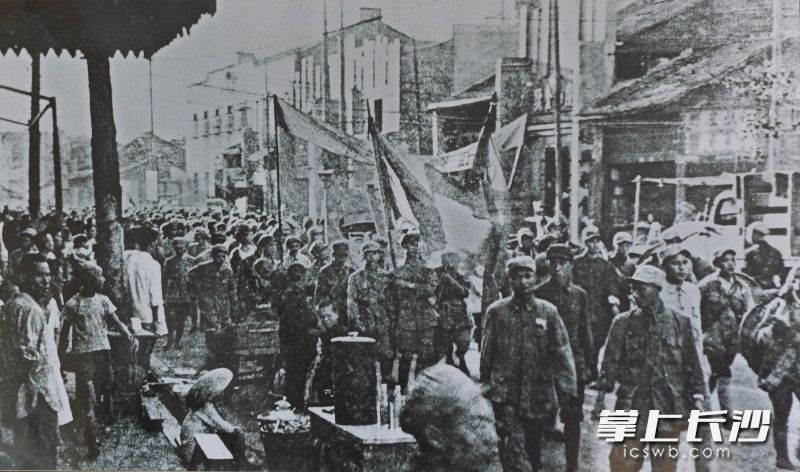 在解放军入城的晚上,本报首位摄影记者游振鑫一直守在又一村中岳楼茶楼前(现长沙市青少年宫)。当解放军队伍来到中岳楼前,游振鑫迅速按下相机快门,拍下了这激动人心的一幕。