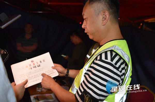 (执法人员现场检查渣土准运许可证.均由星辰全媒体记者 刘宾/摄)