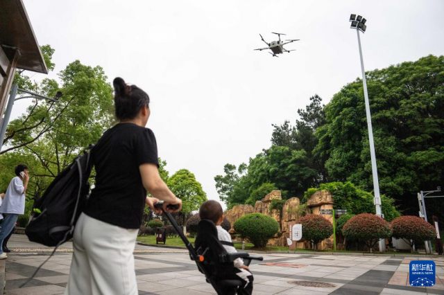 The photo shows residents observing the landing of a UAV loaded with goods at a park in Changsha County. (Photo/Chen Sihan, Xinhua News Agency)