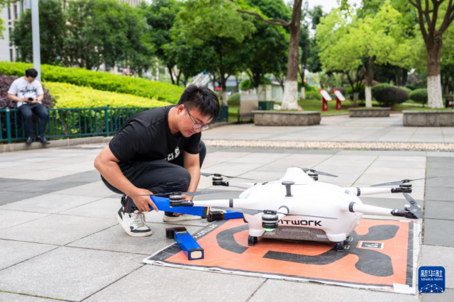 The photo shows a safety staffer replacing batteries for a UAV at a park in Changsha County. (Photo/Chen Sihan, Xinhua News Agency)