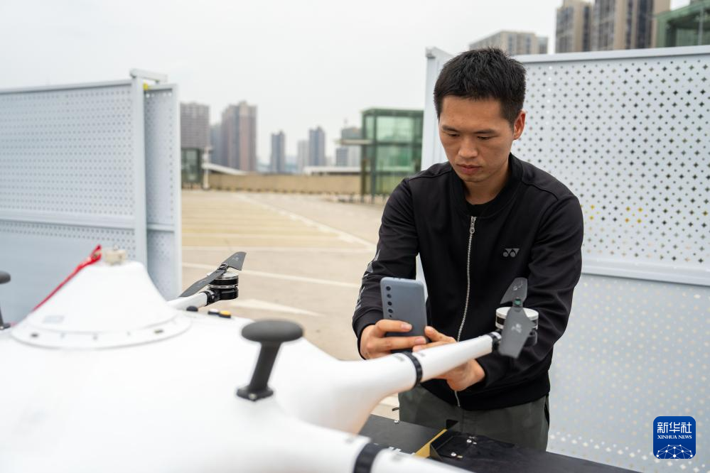 The photo shows a safety staffer taking a photo for a loaded UAV and reporting to the command center for take-off. (Photo/Chen Sihan, Xinhua News Agency)