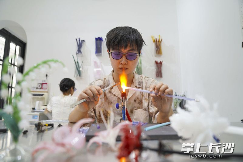 何洋正在制作非遗工艺灯工玻璃，完成一件作品仅要长时间忍受1300℃火焰散发出来的高温。